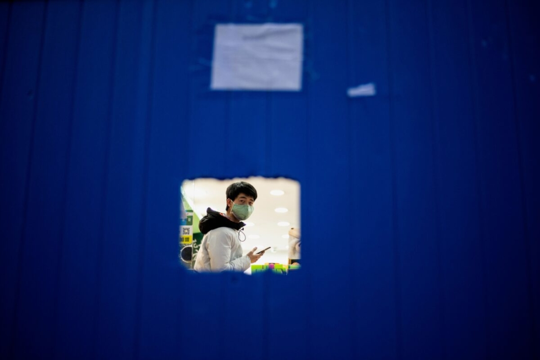Một nhân viên cửa hàng đeo khẩu trang như một biện pháp phòng ngừa trong lúc chờ đợi khách hàng đứng sau hàng rào ở Vũ Hán, ở trung tâm tỉnh Hồ Bắc, Trung Quốc vào ngày 1/4/2020. (NOEL CELIS / AFP qua Getty Images)