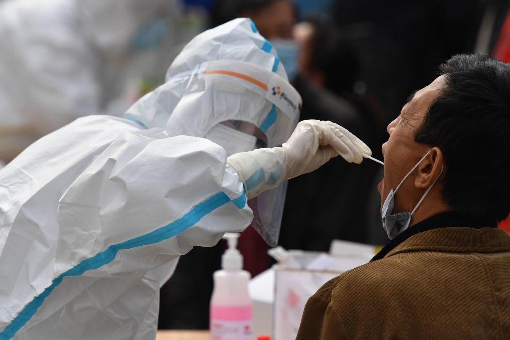 Một nhân viên y tế lấy mẫu tăm bông của một người dân để xét nghiệm virus Corona Vũ Hán - COVID-19, trong khuôn khổ chương trình xét nghiệm hàng loạt sau đợt bùng phát virus corona mới ở Thanh Đảo, một thành phố thuộc tỉnh Sơn Đông ở miền đông Trung Quốc vào ngày 13/10/2020 (STR / AFP qua Getty Images)