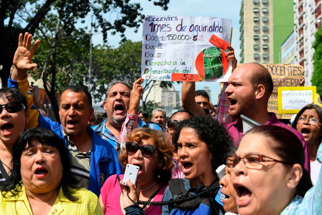 Các giáo viên hô khẩu hiệu trong cuộc biểu tình với những người đã nghỉ hưu do lãnh đạo phe đối lập Venezuela tổ chức ở Caracas, Venezuela vào ngày 20 tháng 11 năm 2019. Venezuela đang ở giữa cuộc khủng hoảng kinh tế và xã hội tồi tệ nhất trong lịch sử gần đây. Theo Quỹ Tiền tệ Quốc tế, lạm phát dự kiến sẽ đạt mức 200.000% trong năm 2019. (Ảnh của YURI CORTEZ / AFP qua Getty Images)