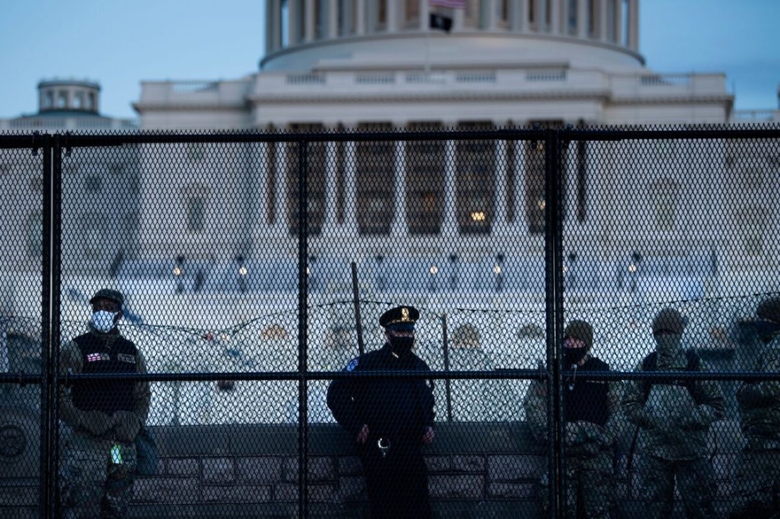 Một sĩ quan Cảnh sát Capitol đứng cùng các thành viên của Lực lượng Vệ binh Quốc gia phía sau hàng rào kiểm soát đám đông xung quanh Đồi Capitol, một ngày sau khi một nhóm đột nhập vào Điện Capitol của Hoa Kỳ ở Washington, vào ngày 7/1/2021. (Brendan Smialowski / AFP qua Getty Images)